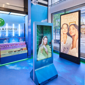A Sephora store interior featuring colorful displays of beauty products. A digital screen shows a model, and a large poster nearby showcases two smiling women. The space is brightly lit with a modern design.