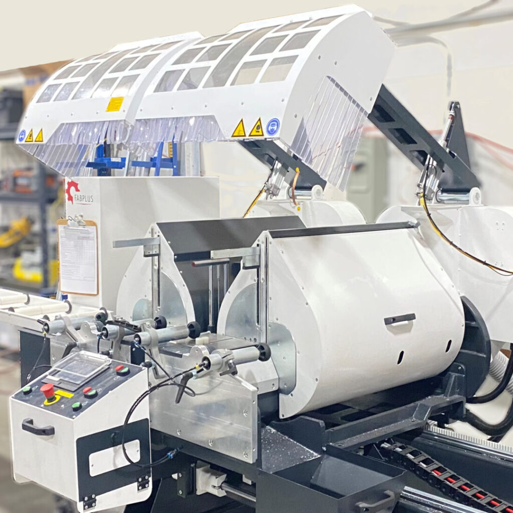 A large industrial machine with white and silver components, featuring two circular saw blades, a control panel with buttons, and a conveyor belt. It stands in a workshop filled with tools, echoing the history of Shomi! with its cutting-edge design and innovation.